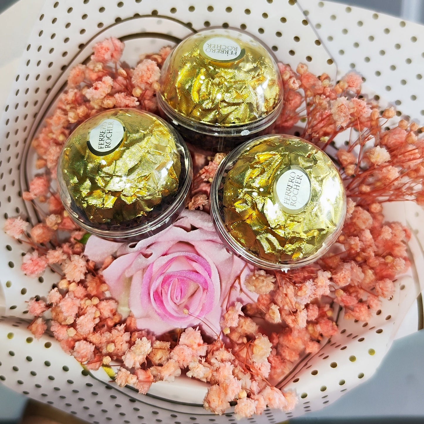 A small bouquet of flowers with pink Baby  breath's flowers and 1 artificial rose and paired with 3 Ferrero Rocher Chocolates.