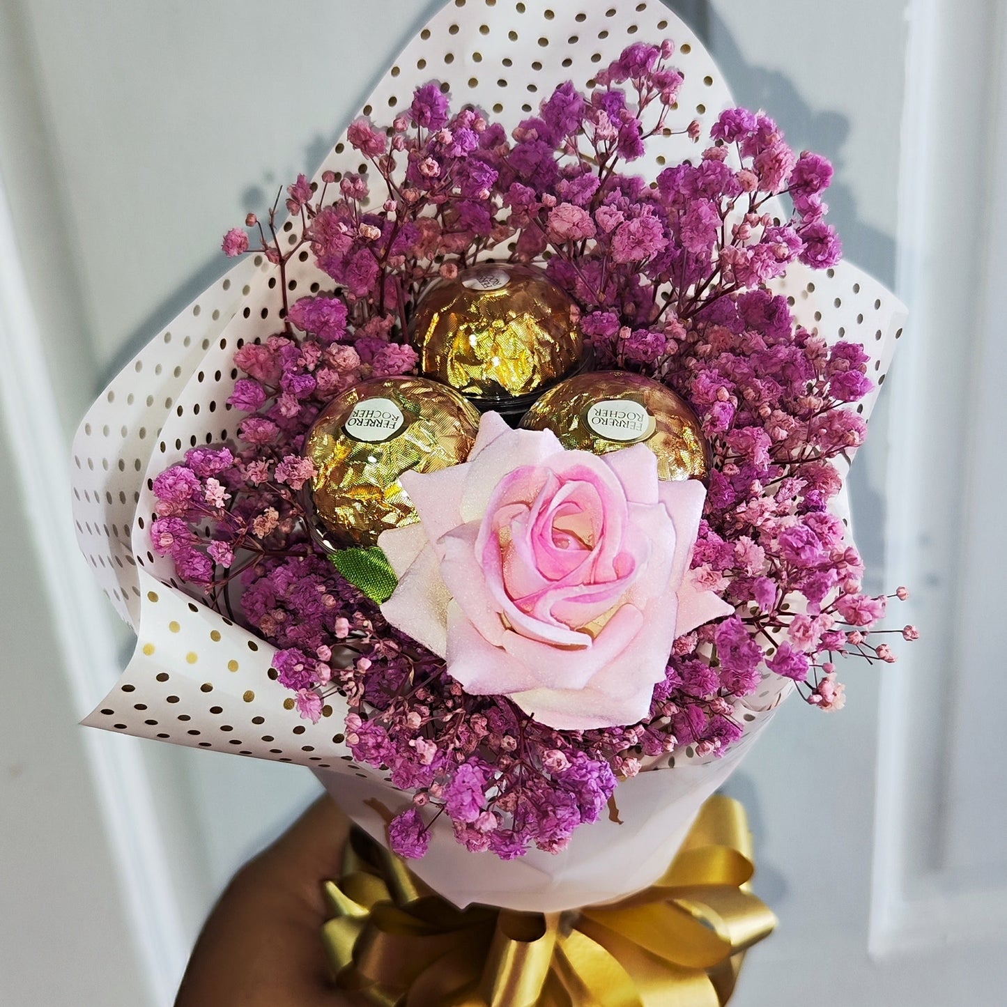 A small bouquet of flowers with purple baby  breath's flowers and 1 artificial rose and paired with 3 Ferrero Rocher Chocolates.